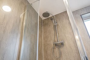 Una ducha moderna con cabezal de ducha manual y grifería empotrada.