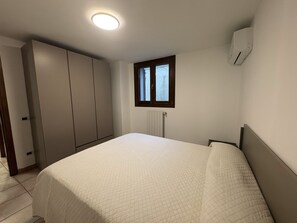 Une chambre comprenant un lit, une armoire, une fenêtre et un système de climatisation intégré.