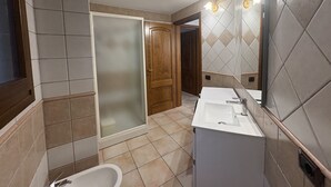 Et badeværelse med bruser, toilet og vask.