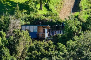 A cabin surrounded by dense forest, with a wooden deck and a small porch. - Tiny House Jaulares (Rivas)