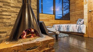Une pièce chaleureuse avec une cheminée, un lit et de grandes fenêtres.