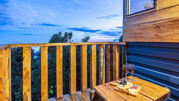 Une terrasse en bois avec une table dressée pour un repas, donnant sur une zone boisée.