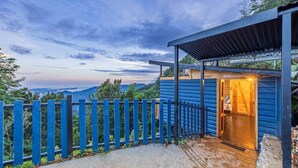 Un bâtiment moderne avec une porte en bois, une clôture bleue et une vue sur le paysage.