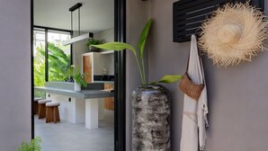 Una cucina moderna con un'ampia finestra, un vaso alto con piante e un cappello di paglia appeso al muro.