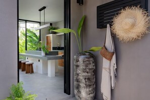 Eine moderne Küche mit einem großen Fenster, einer hohen Vase mit Pflanzen und einem gewebten Hut an der Wand.
