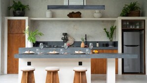 Una cucina moderna con isola centrale, sgabelli di legno e frigorifero in acciaio inossidabile.