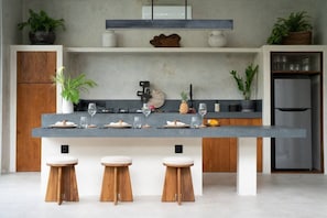 Eine moderne Küche mit einer zentralen Kochinsel, Holzstühlen und einem Edelstahl-Kühlschrank.