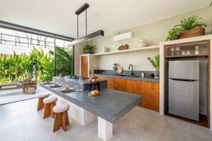 Eine moderne Küche mit einer großen Kochinsel, Holzstühlen und einem integrierten Kühlschrank.