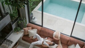 Un soggiorno moderno con vista piscina, un divano, un tavolino da caffè e una scacchiera.