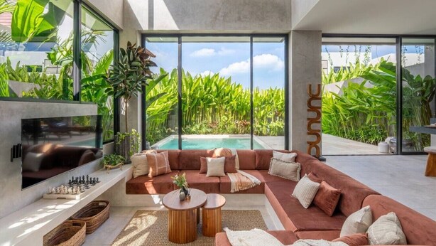Un soggiorno moderno con piscina, ampie finestre e piante tropicali.