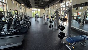 Une salle de sport équipée de tapis de course, d’appareils de musculation et d’un mur recouvert de miroirs.