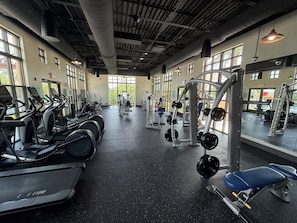 Ein Fitnessstudio mit Laufbändern, Kraftgeräten und einer Spiegelwand.