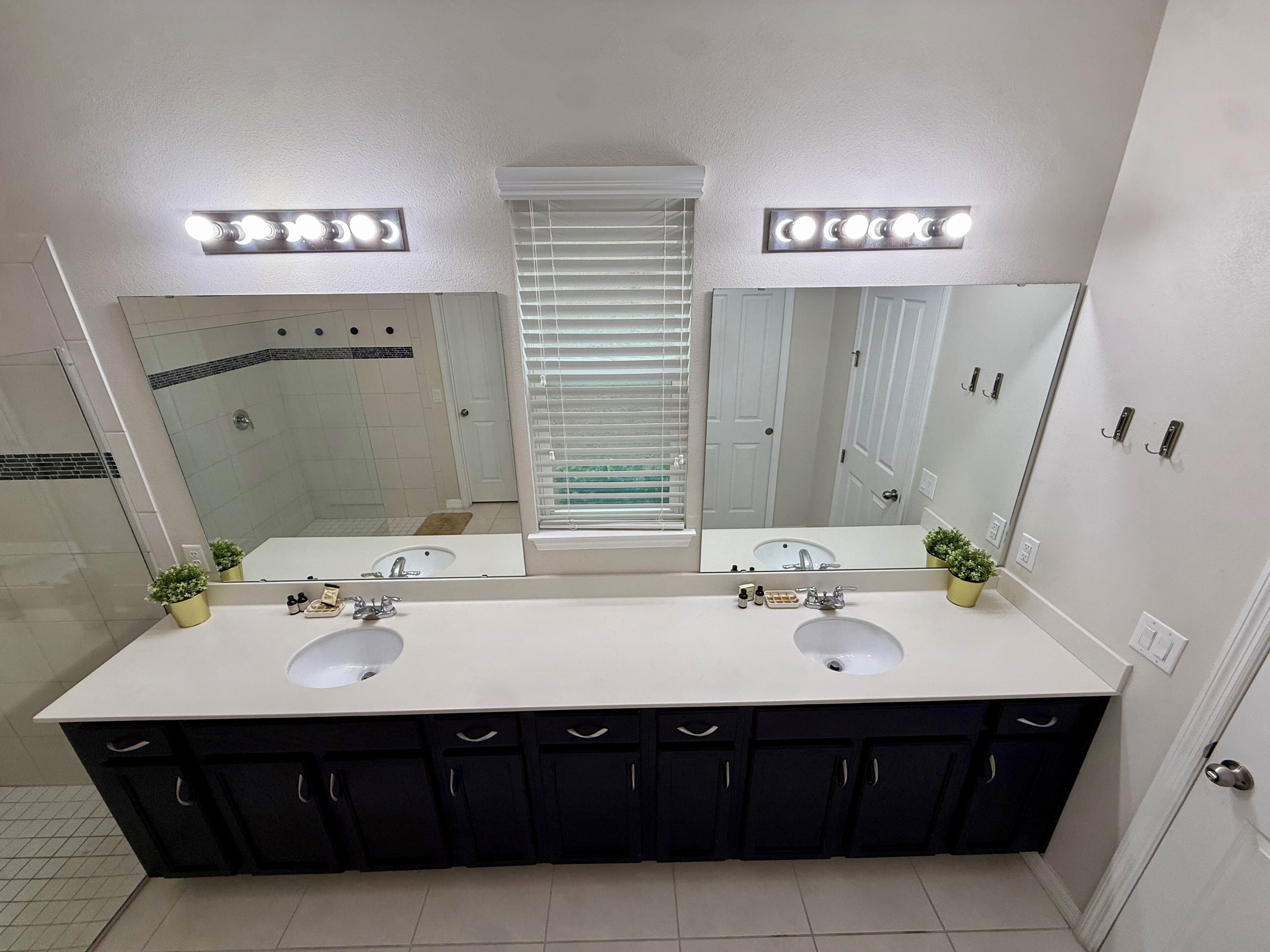 Un baño con dos lavamanos, un espejo grande e iluminación en el techo.