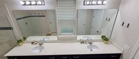 Un baño con dos lavamanos, un espejo grande e iluminación en el techo.