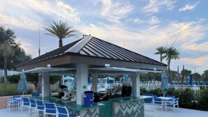 Un espace bar extérieur avec un comptoir, des chaises et des parasols.