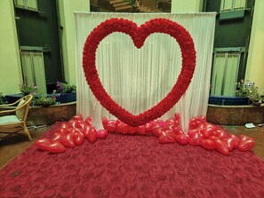 A heart-shaped floral arrangement on a red carpet with a backdrop of vertical drapes. - Rose View Hotel (Sylhet)