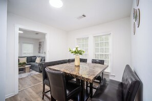 A dining area with a marble table, black leather chairs, and a vase with flowers.