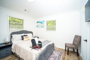 A bedroom with a bed, bedside tables, a chair, and artwork on the walls.