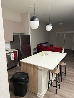 Eine moderne Küche mit Kochinsel, Barhocker, einem roten Sofa und einem Deckenventilator.