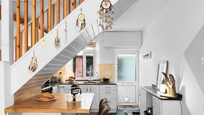 Eine moderne Küche mit einer Holztreppe, einem Essbereich mit Tisch und Stühlen sowie Blick zum Wohnbereich.