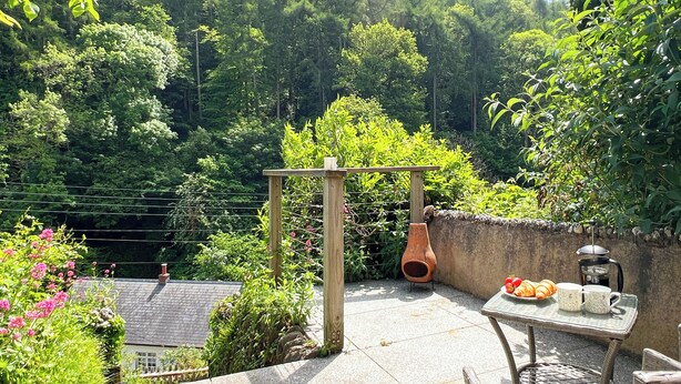 Eine Terrasse mit Tisch, Stühlen, einem Terrakottatopf und einer Holz-Pergola.