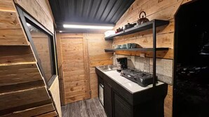 A compact kitchen with wooden walls, a built-in stove, and a small sink.