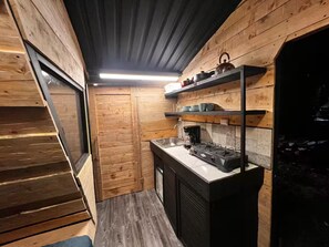 A compact kitchen with wooden walls, a built-in stove, and a small sink.