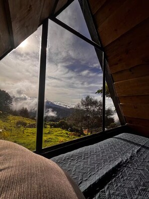 A room with a large window offering a view of a mountainous landscape.