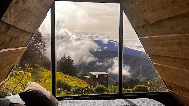 A room with a large triangular window offering a view of a mountainous landscape.