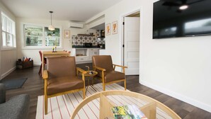 A living room with brown leather chairs, a coffee table, and a TV mounted on the wall. - Cottage AND Tiny House on Lake Pontoon Available (Lake Lure)