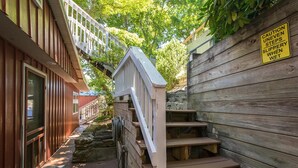 A wooden staircase with a caution sign warning of uneven steps when wet. - Cottage AND Tiny House on Lake Pontoon Available (Lake Lure)