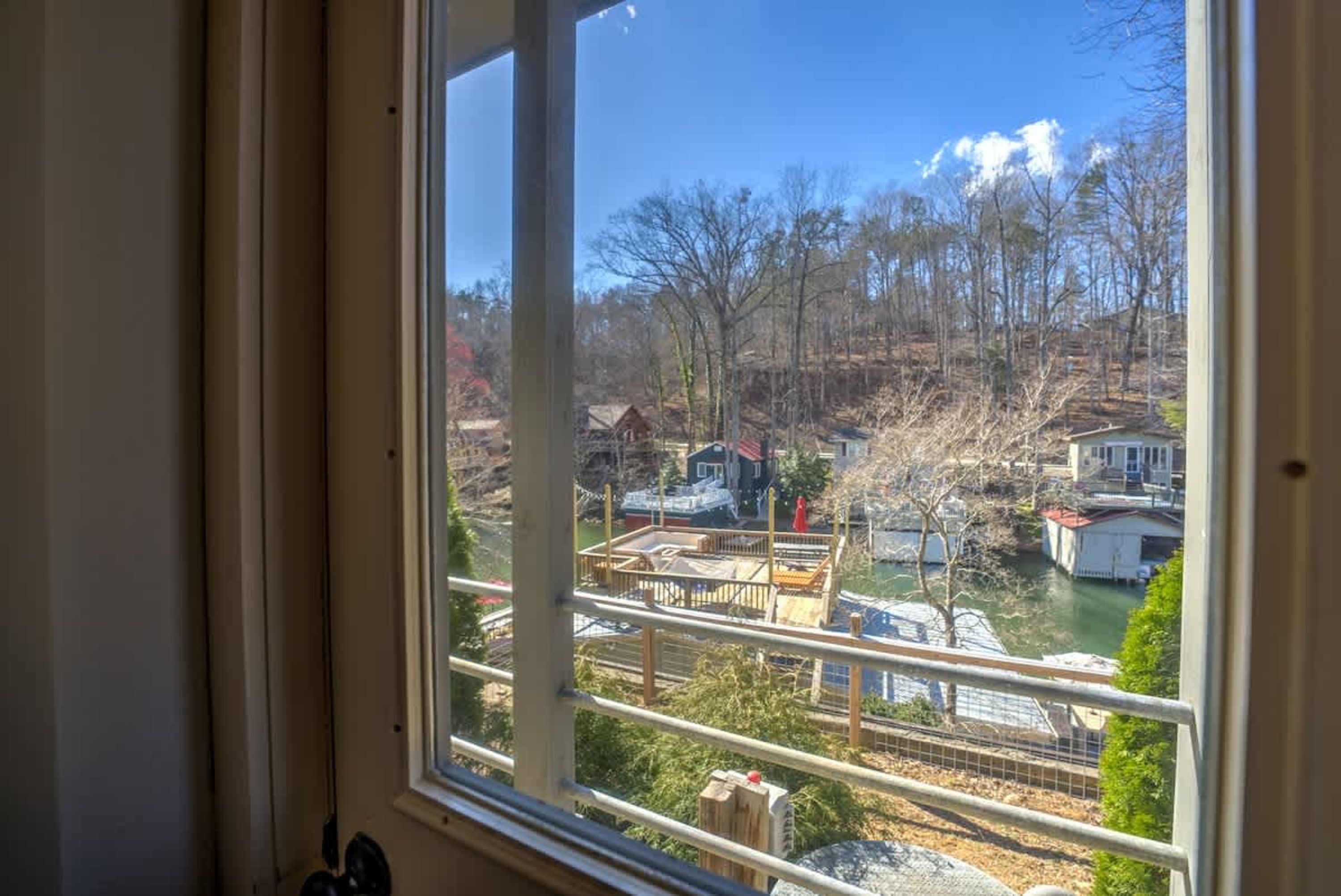 A view through a window of a residential area with houses, a dock, and a river.