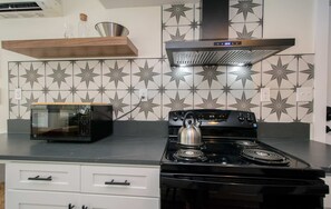 Una cocina con microondas, estufa y azulejos decorativos.