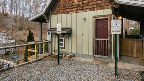 A rustic building with a wooden exterior, a metal railing, and a gravel driveway. - Cottage AND Tiny House on Lake Pontoon Available (Lake Lure)