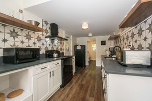 Una cocina moderna con armarios blancos, una estufa negra, un microondas y un tostador.