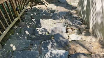 A stone staircase leading up to a wooden deck with a caution sign for a steep slope.