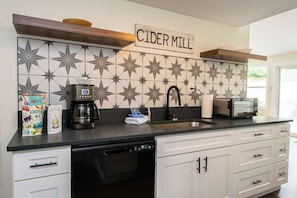 A kitchen with a coffee maker, a toaster, and a coffee machine on the counter. - Dog Friendly Cottage on Lake Pontoon Available (Lake Lure)