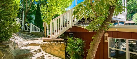 Una escalera de madera que lleva a una cabaña con una pared de piedra y una ventana.