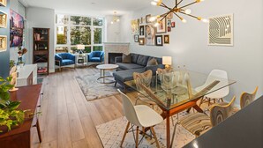 Ein modernes Wohnzimmer mit einem Glastisch, blauen Sesseln, einem grauen Sofa und einem Kamin.