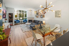 Ein modernes Wohnzimmer mit einem Glastisch, blauen Sesseln, einem grauen Sofa und einem Kamin.