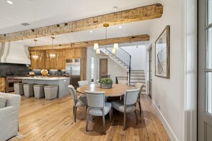 Una cocina moderna con vigas de madera, una isla central y un comedor con sillas.
