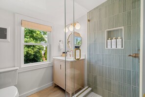 Une salle de bain comprenant des toilettes, une fenêtre, une douche en verre et un lavabo avec un miroir.