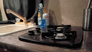 Een keuken met een gasfornuis, een spoelbak en een fles afwasmiddel.