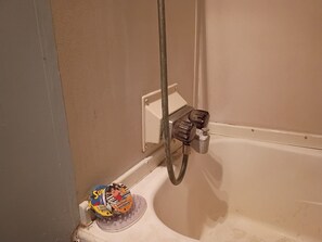 Una ducha con cabezal de ducha manual, jabonera y dispensador de jabón.