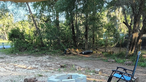 Een camping met een vuurkuil, een stoel en een hangmat.