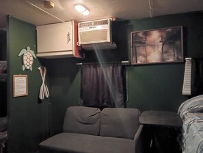 A room with a sofa, an air conditioning unit, a framed picture, and a wall-mounted sign. - RV stay private land 
The Angler's Hideout 
Close to springs, parks, & Daytona (Paisley)