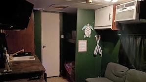 Een compacte kamer met een kitchenette, een bank en een kleine tafel.