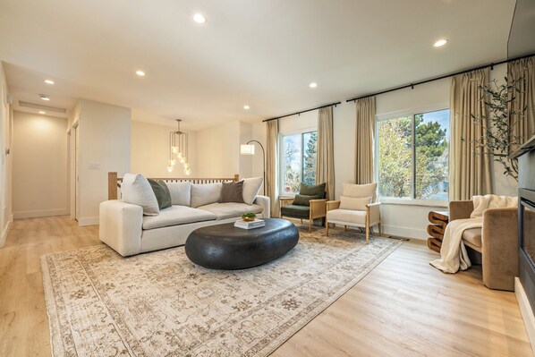 A modern living room with a sofa, armchairs, a coffee table, and a TV.