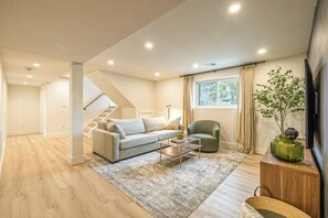 A modern living room with a sofa, armchair, coffee table, and a TV.