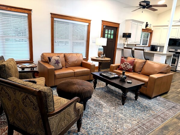 Una sala de estar con sofá, sillón, mesa de centro y alfombra estampada.